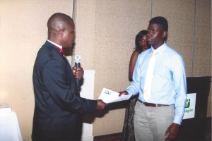 The president of the League of Committed Friends, Emmanuel Okunmwendia presents scholarship award to Daniel Ssozi, a 2015 graduate of Lynn Classical High School, while Erhonmwon Adenomon who read the citation looks on.